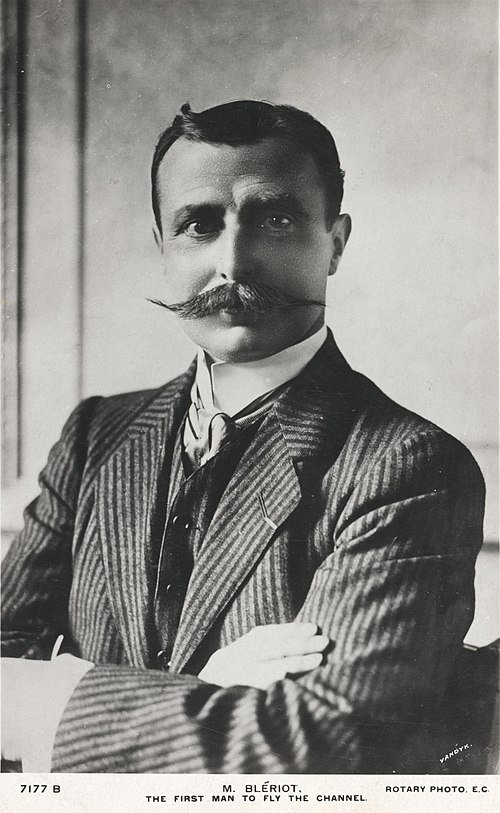 Portrait of French aviator Louis Blériot beside his monoplane.